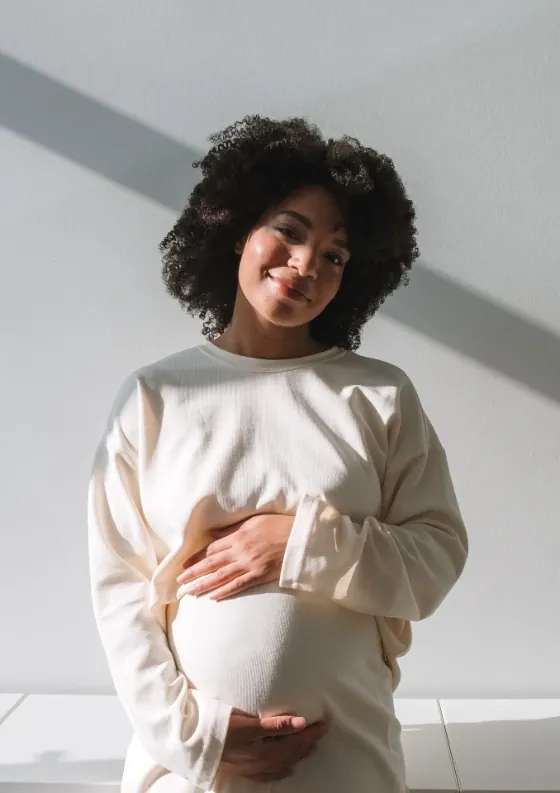 A pregnant woman smiling and touching her belly